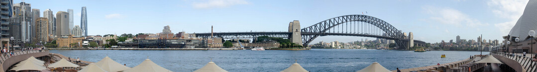 Panoramic view of Circular Quay, The Harbour Bridge, Syndey Harbour, and the edge of the Opera House